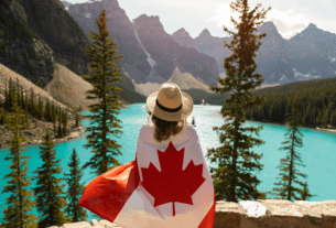 Uma mulher com a bandeira do canada, parada em frente a um logo