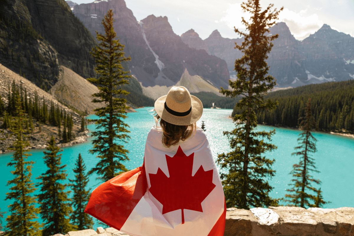 Uma mulher com a bandeira do canada, parada em frente a um logo